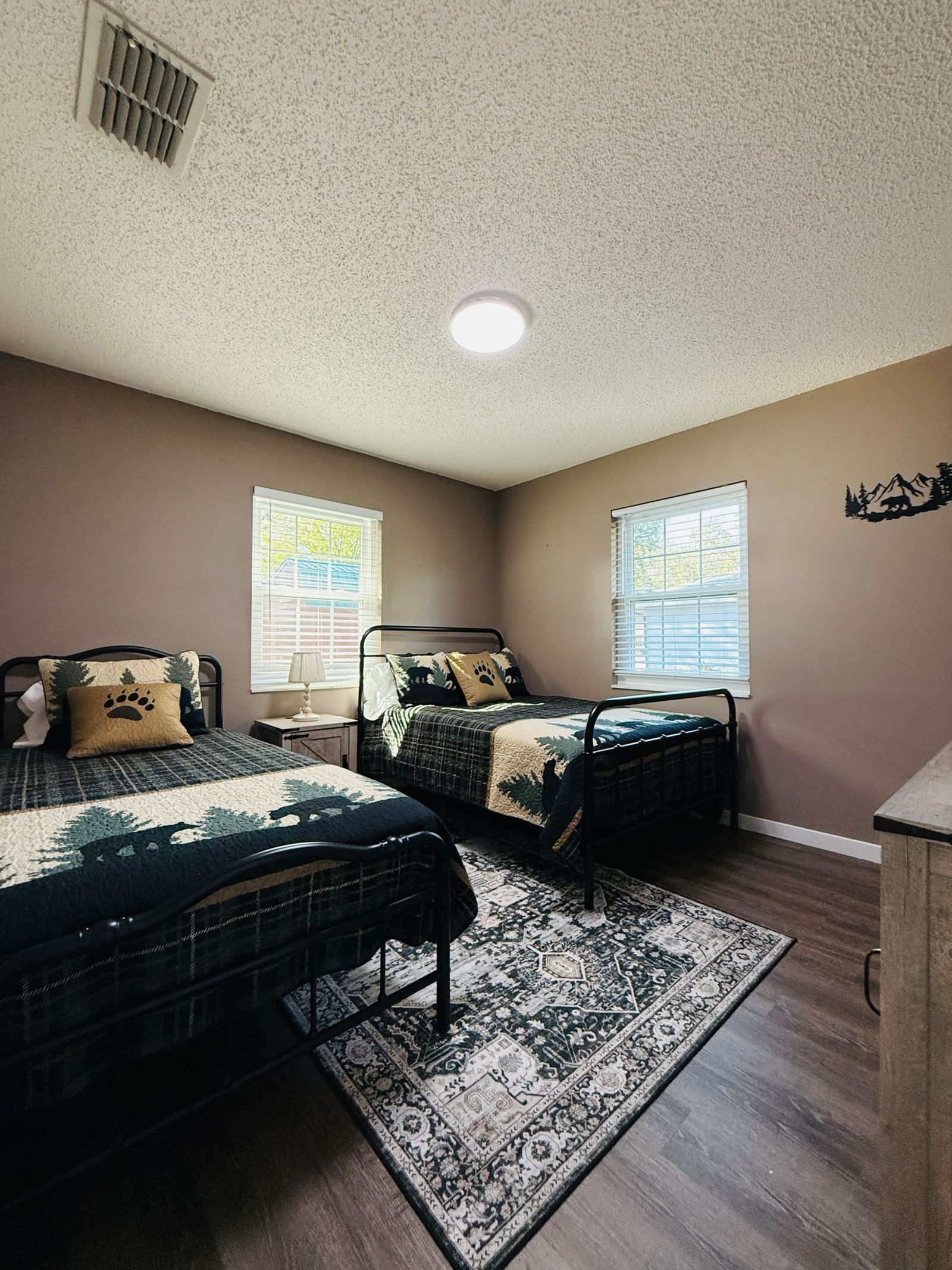 Lodge-themed second bedroom with two beds and bear cabin quilts