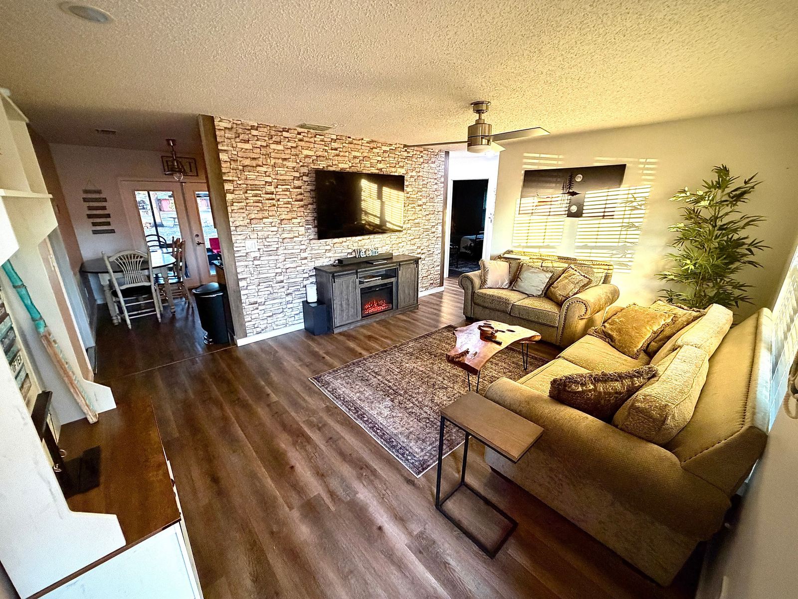 Living room with stone accent wall, electric fireplace, and 65-inch smart TV